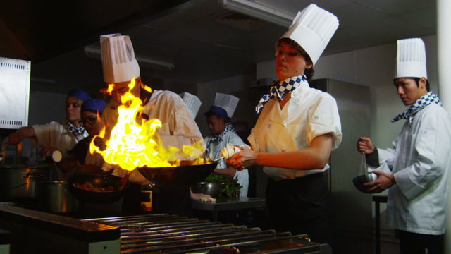 Professional chef in a restaurant kitchen cooking flambe style