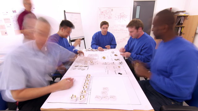 Time lapse of male workers in a factory assembling electrical fittings