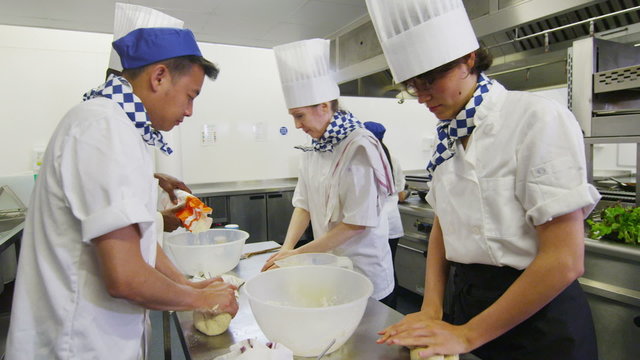 Chefs in restaurant or bakery kitchen preparing dough for bread or pastry