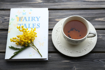 Fairy Tales book with cup of tea and sprig of mimosa