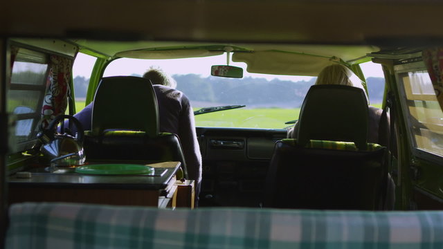 Attractive couple in camper van lean over to share a kiss