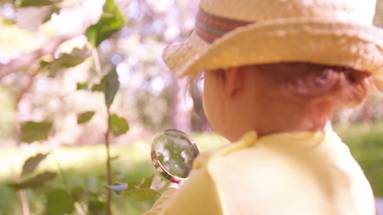 Curious toddler studying a leaf with a magnifying glass