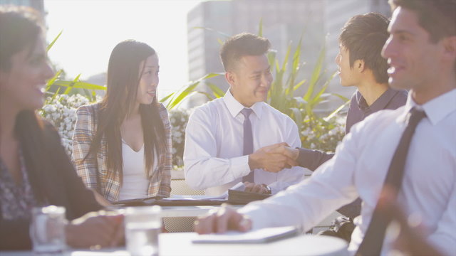 Young asian business team in open air meeting in the city shake hands on a deal