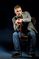 portrait of young negligent man with cane sitting on chair