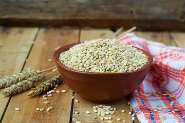 Pearl barley in a ceramic bowl on a wooden background.selective