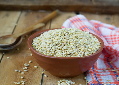 Pearl barley in a ceramic bowl on a wooden background.selective