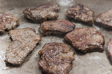 Beef steaks cooking on graill at at restaurant buffet