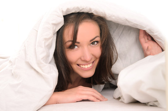 smiling young attractive woman covered with blanket