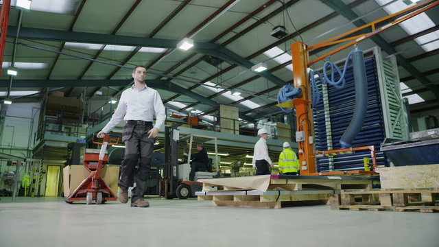 Team of busy warehouse workers lifting and moving empty pallets and boxes
