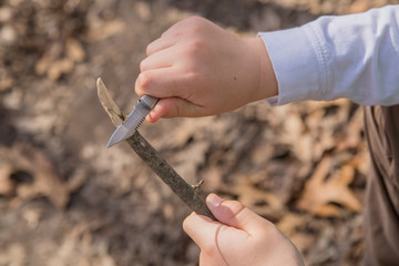 Hands of a young boy whittling a piece of wood