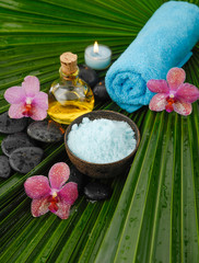 Fototapeta na wymiar Spa set with spa oil ,towel salt in bowl , orchid on palm leaf