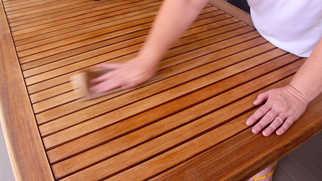 Person sanding a wooden table to prepare it for varnishing.