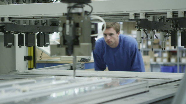 Male machine operator in a factory checking the process