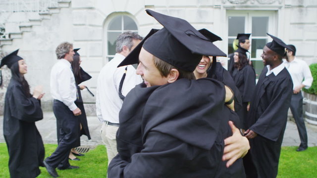 Happy student friends hugging and congratulating each other on graduation day