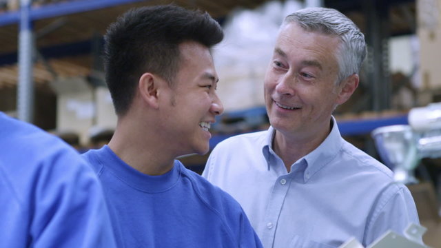 Happy male factory worker discussing work with his line manager