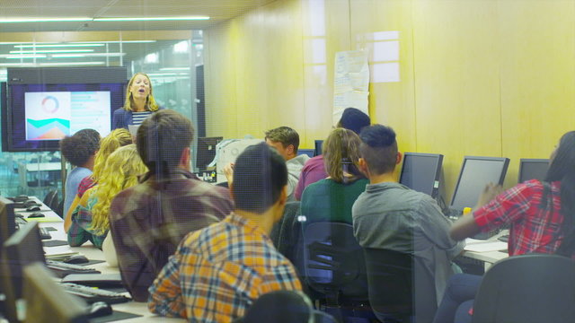 Female teacher teaching group of college students in a computer class