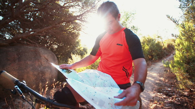 Orienteering mountain biker navigating with a map