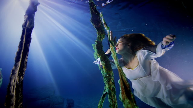 Beautiful mysterious underwater woman in white dress