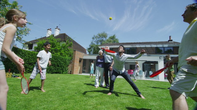 Family & friends of many generations playing sports in the garden on a sunny day