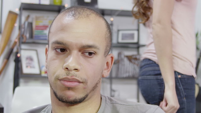 A young man sits quietly and refuses to be drawn into an argument although we can see his partner in the background, pacing up and down and shouting. In slow motion.