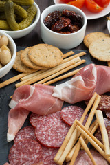 Assorted meat snacks, sausages and pickles on a blackboard