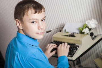Fototapeta na wymiar the boy sits at the typewriter