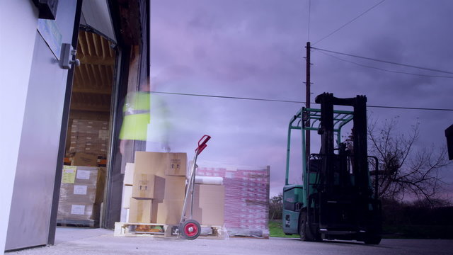 Time-lapse clip with warehouse workers loading pallets and moving them around