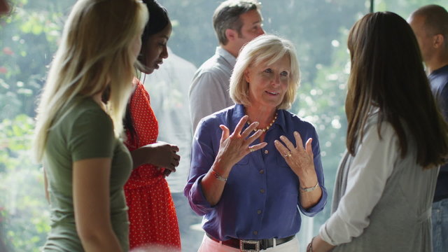 Female friends or casual business colleagues chatting together at a social event