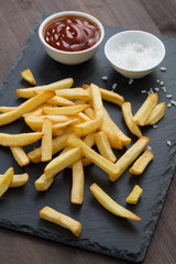fried French fries, tomato sauce and salt on a blackboard