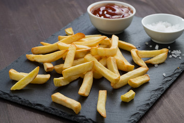 fried French fries, tomato sauce and salt on a blackboard