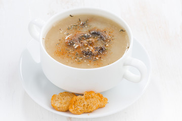 mushroom cream soup with croutons on white wooden table