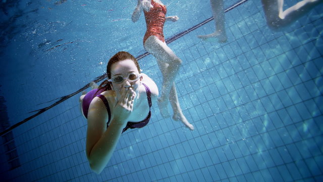 Young female friends in a swimming pool having fun together underwater