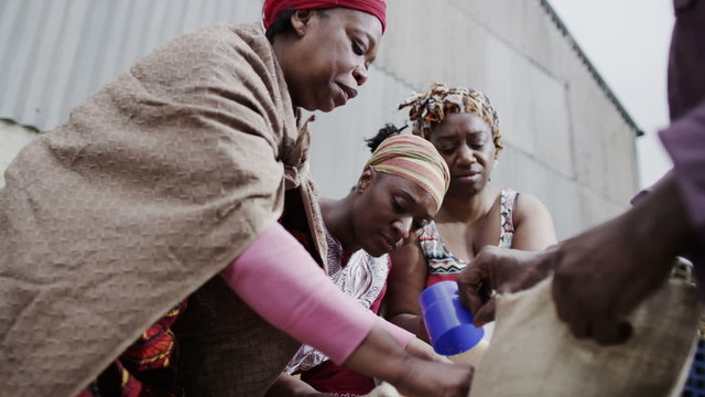 African family working together, measuring out quantities of rice or grain