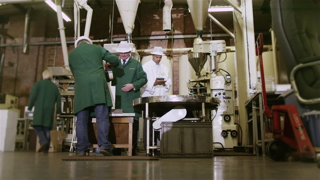 Workers in a beverage factory sorting and packing packets of fresh coffee