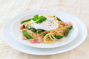 Poached egg on spaghetti with green asparagus