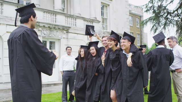 Happy student friends taking pictures of each other on graduation day