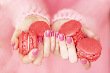 Women's hands with a beautiful pink manicure holding macaroones