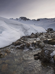 Mountain creek and snow capped peak at dawn