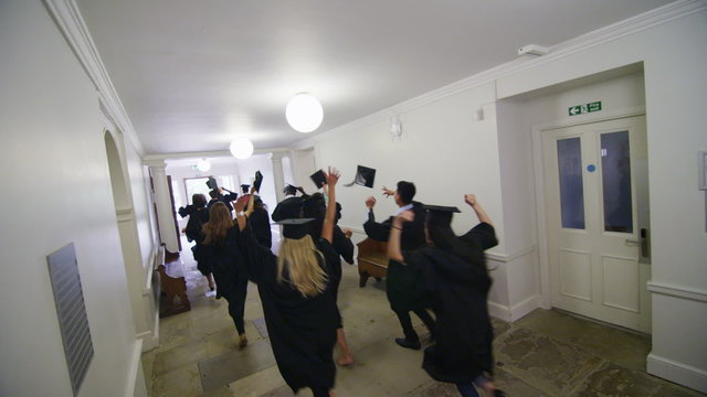 Excited group of students on graduation day running through the hallway