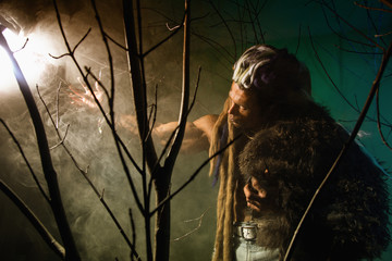 Muscular man with skin and dreadlocks looking at a bright light