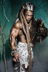 Muscular man with skin and dreadlocks among the trees