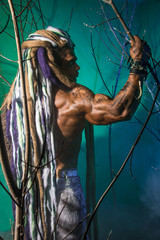 Muscular man with dreadlocks in the forest