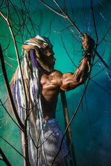 Muscular man with dreadlocks in the forest