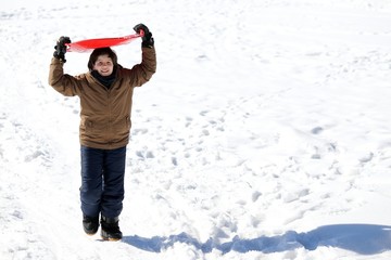 young boy walks with tobogganing on the head on fresh snow