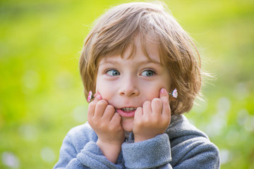 Closeup portrait of a cute little boy on light green park backgr