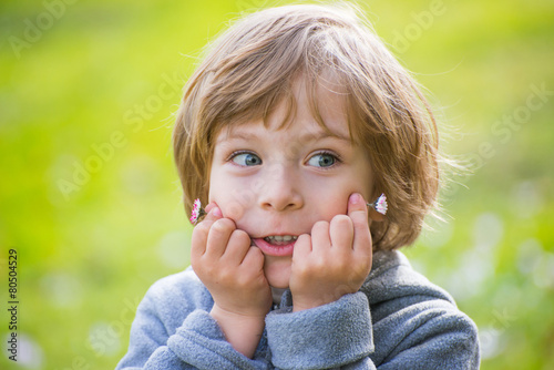 Closeup portrait of a cute little boy on light green park backgr
