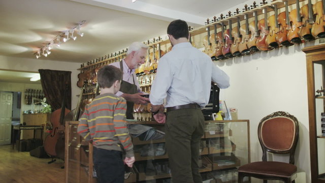 Father and son shopping together, make a purchase in a musical store