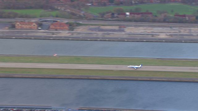 Aerial view of a plane taking off from a runway by the side of the river thames