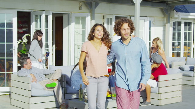 Portrait of happy attractive couple socializing with friends outside beach house