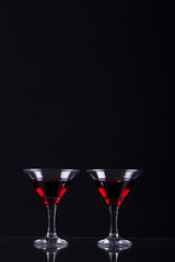 Red wine in a two glasses of martini on a black background